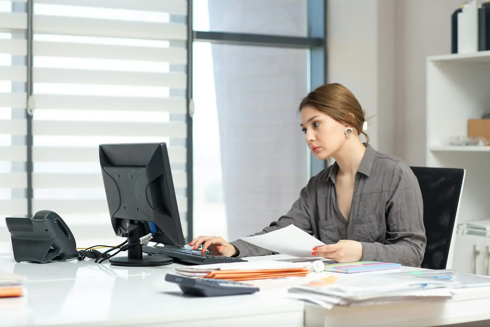 Business owner working through documents and a computer at an office desk