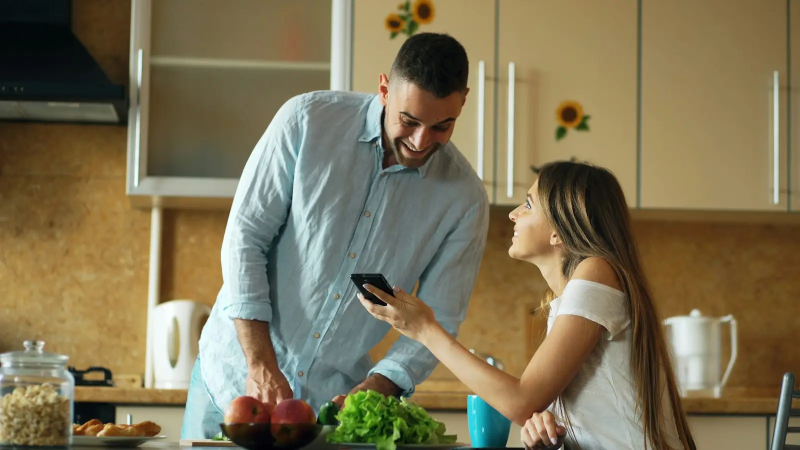 Couple checking a phone together at the kitchen bench