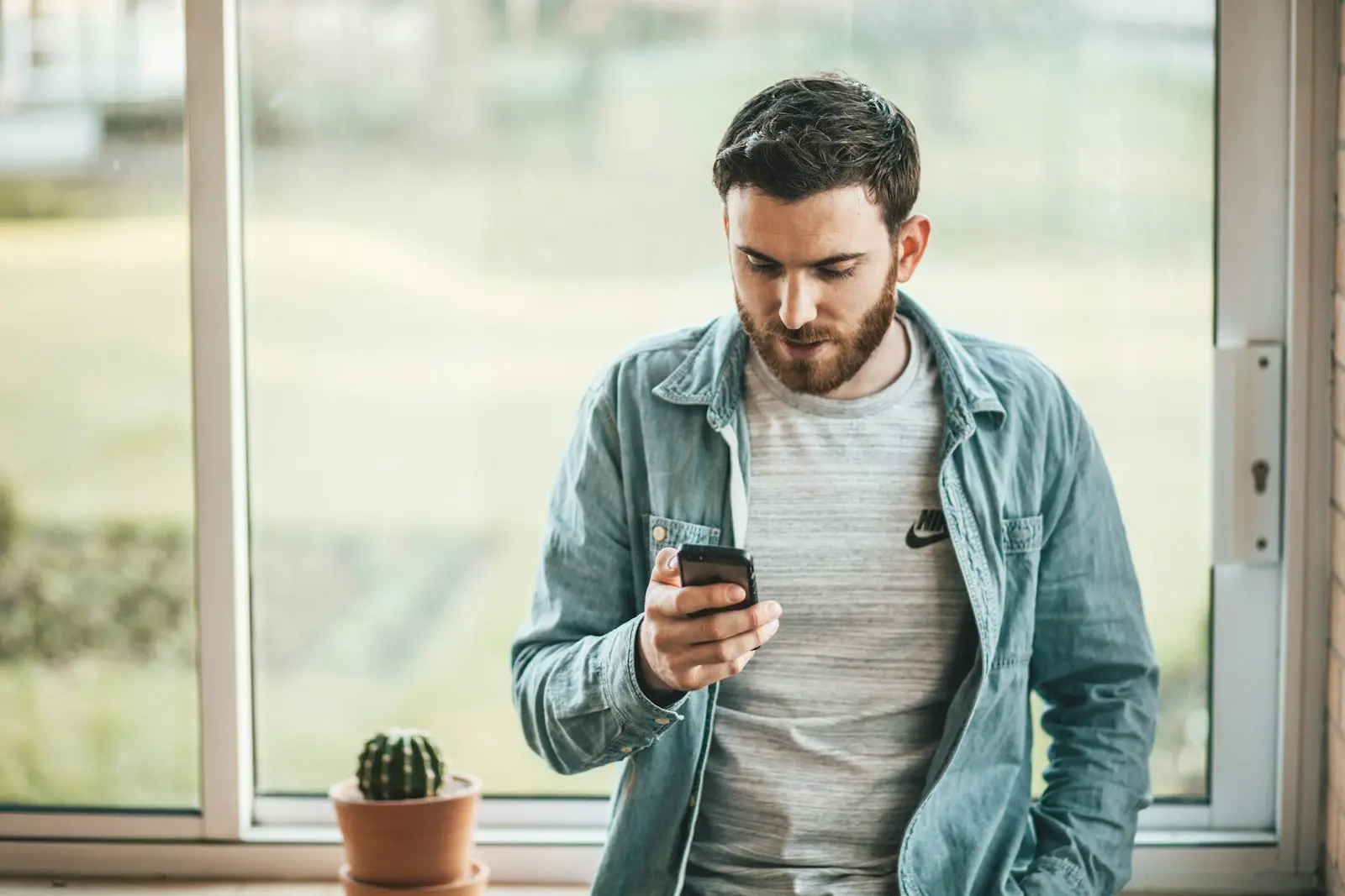 Man reading a message on his smartphone by a window