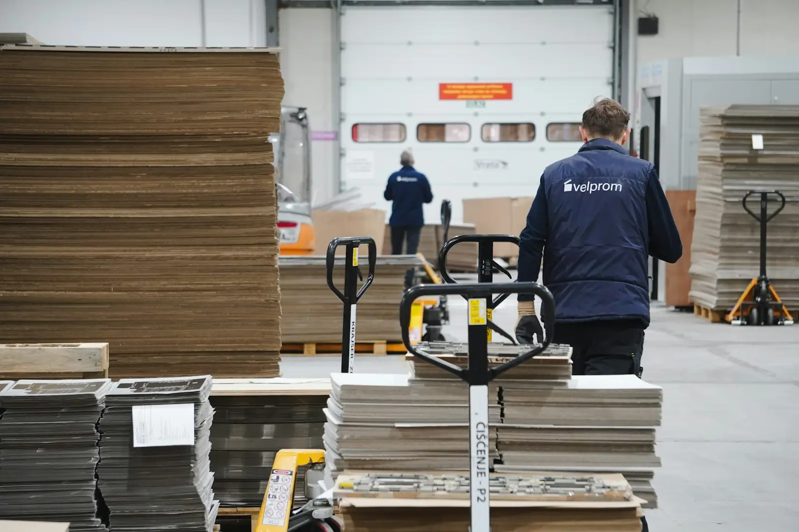 Worker moving a trolley of boxed stock through a warehouse